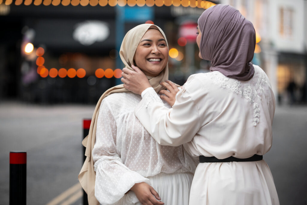 deux femmes voilées souriante, l'une touche le hijab de l'autre 